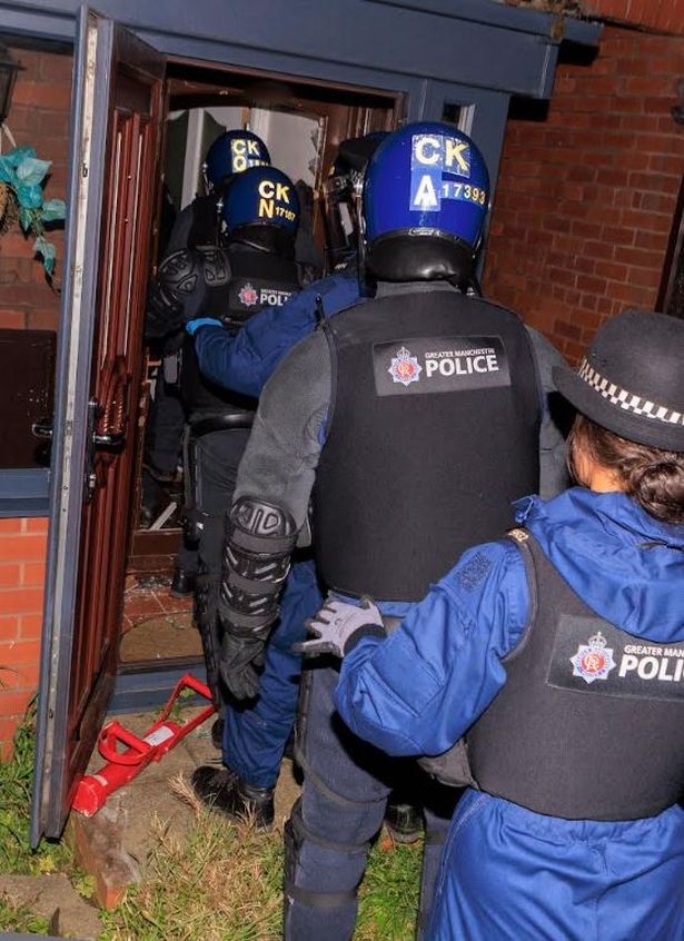 Operation Vulcan officers storm a home in Derker, Oldham, today.