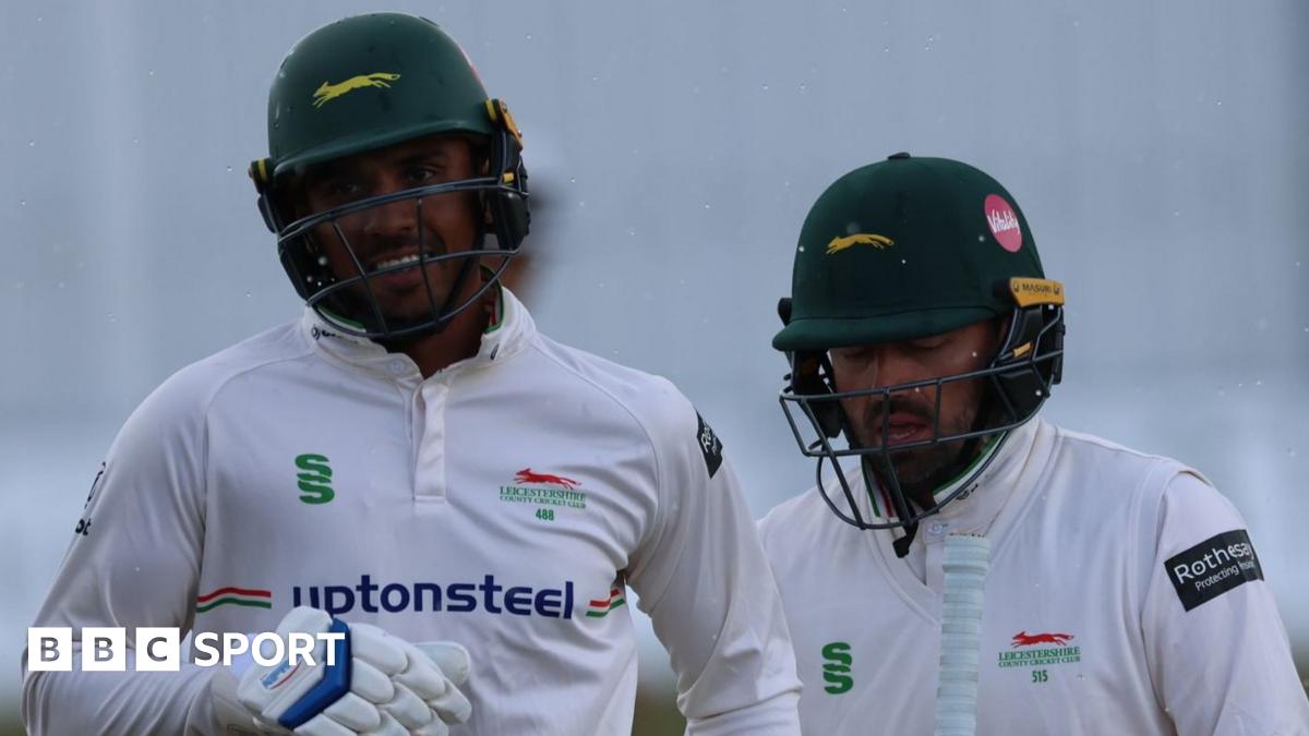 Rishi Patel and Ian Holland walking from the field as rain falls