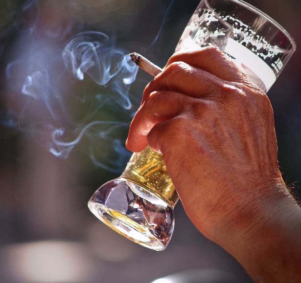 an old man sitting at the table in outdoor pub Drinking beer and smoking
