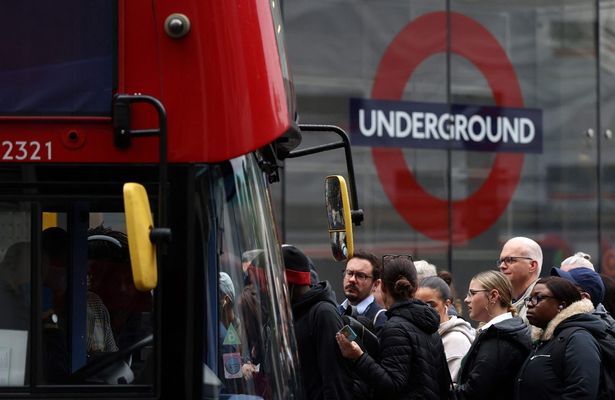 Commuters attempt to board a bus outside Victoria train station in London
