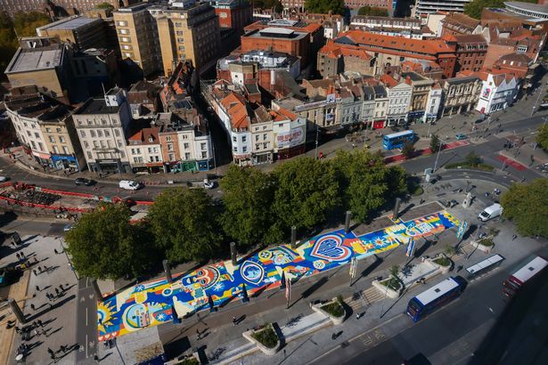 “Our Common Ground” by artist Oshii transforms Centre Promenade into a bold celebration of heritage, identity and unity
Bristol has a powerful new landmark. Our Common Ground, a monumental street-level artwork by multidisciplinary artist Oshii, has been officially completed in the city centre, reimagining the busy Centre Promenade as a vibrant space for cultural connection, reflection and pride.
Spanning more than 700 square metres, the vivid mural is now a striking feature of the city’s public realm. Its unveiling marks a major milestone in the transformation of Bristol’s central spaces, placing African heritage and community voices at the heart of civic life.  Monday 29 September 2025