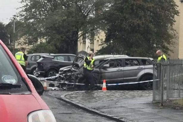 Three officers standing around the torched vehicle