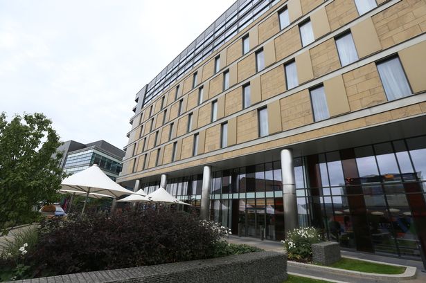 A modern city hotel building with gardens outside