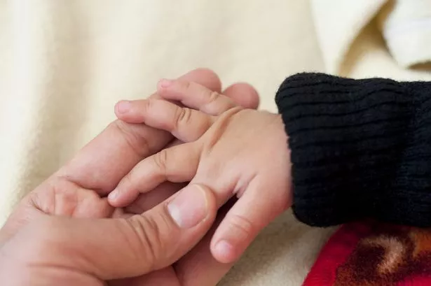 Generic image of parent and baby holding hands