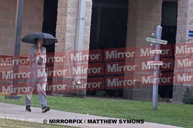 Ghislaine Maxwell holds her umbrella as she walks on prison grounds