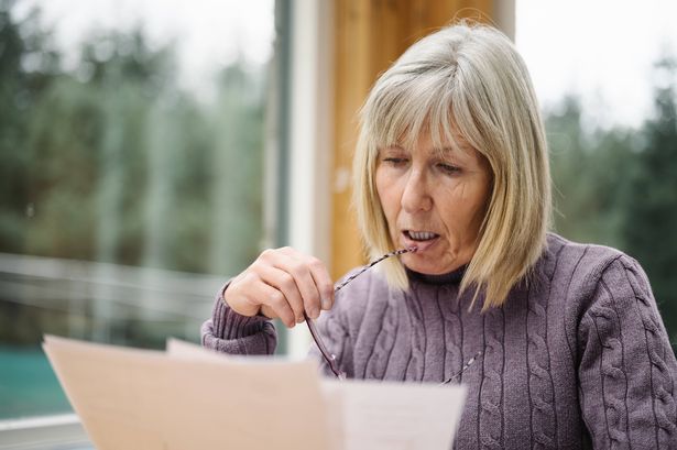 Worried senior woman examining a bill she just received through the post.