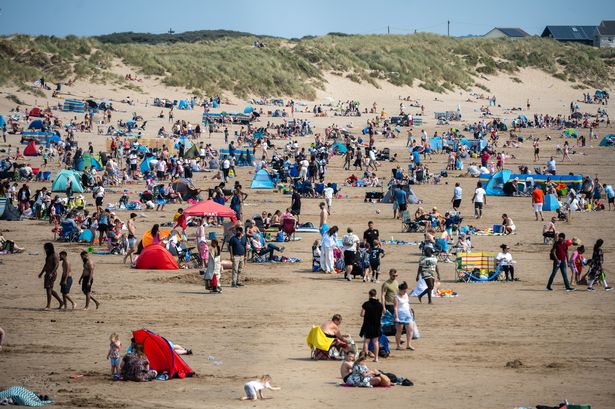 A packed beach with lots of revellers young and old on a particularly sunny and warm day