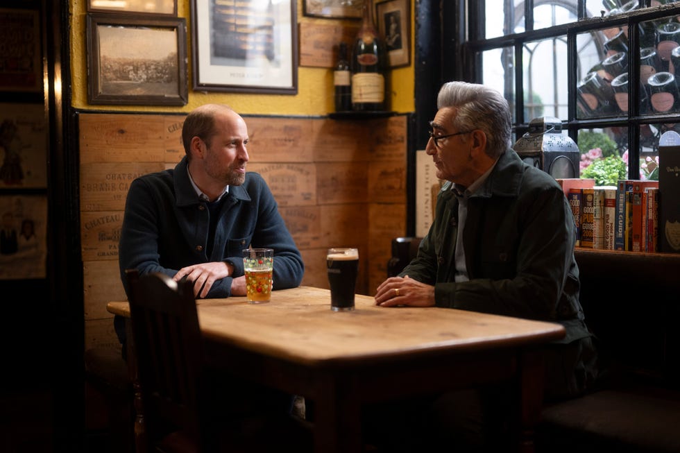 Two individuals engaging in conversation at a wooden table.