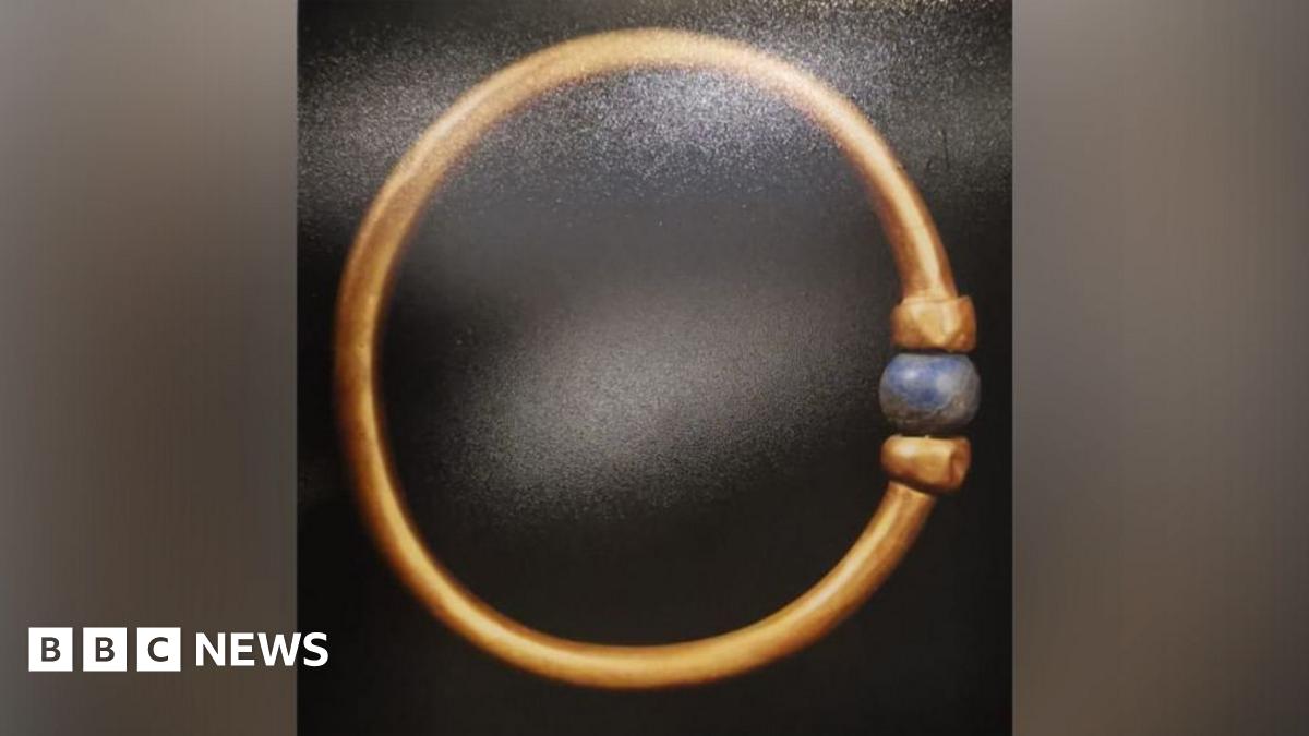 The Bracelet is gold and adorned with a blue, round bead.