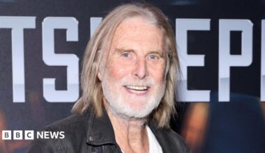 David Threlfall smiling with shoulder-length hair and grey beard