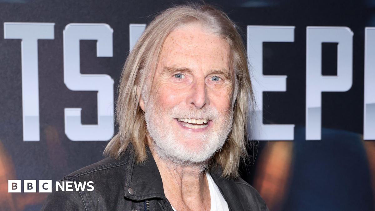 David Threlfall smiling with shoulder-length hair and grey beard