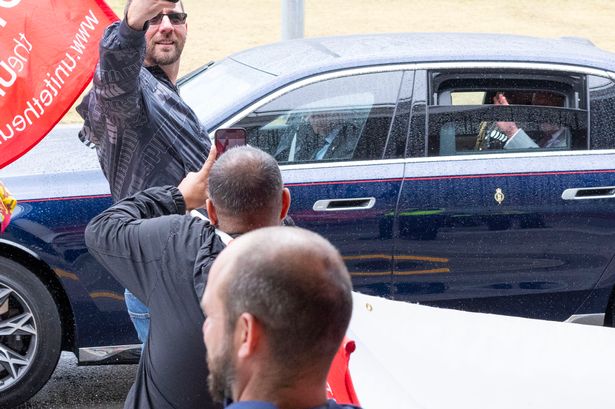 The King waved to bin strike protesters from his car bearing the royal standard
