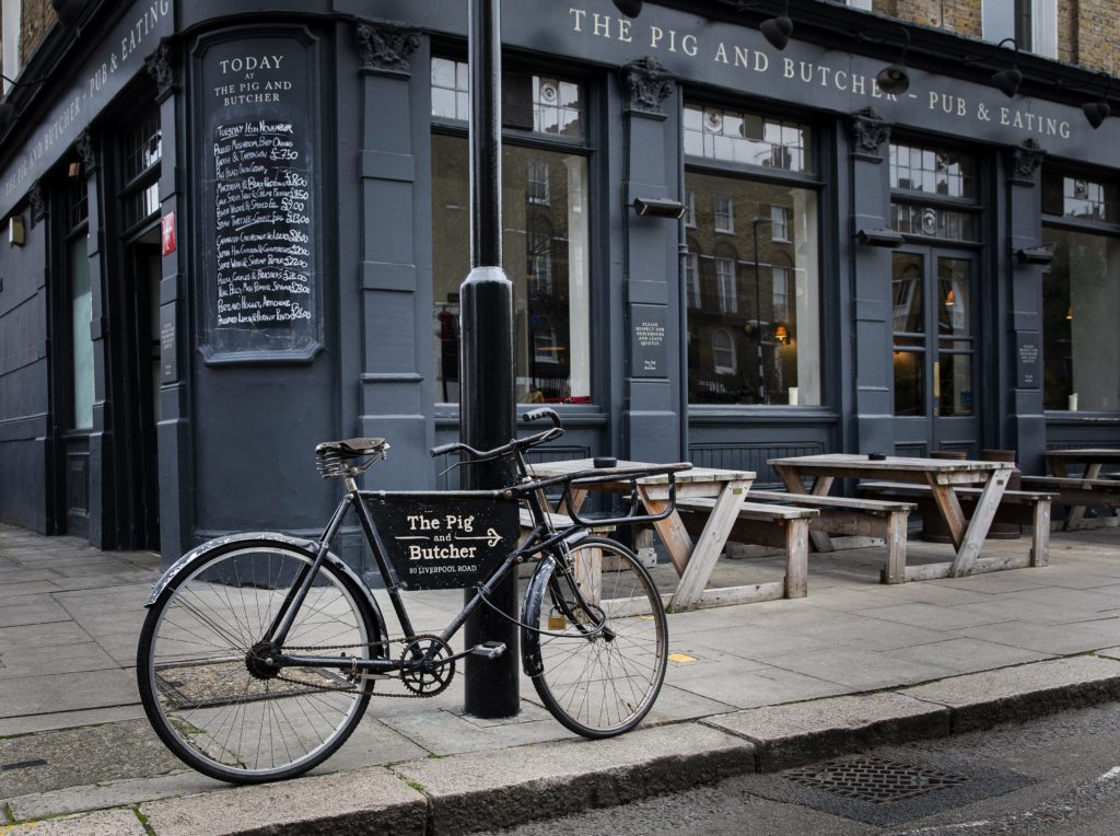 a bike, advertising the pig and butcher in a sign across its frame, parked outside the pig and butcher
