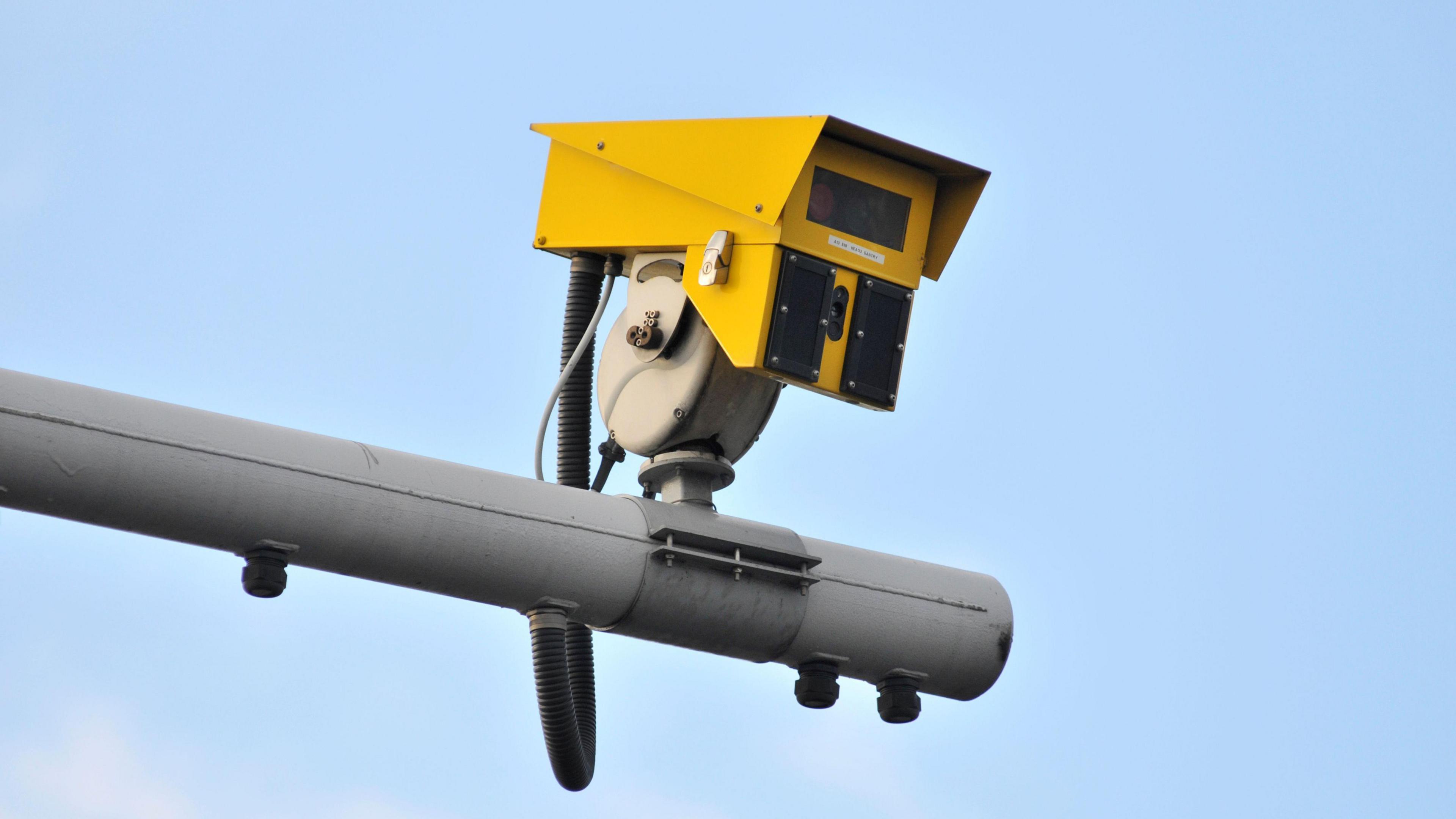 An average speed camera, coloured yellow, and sitting on a traffic pole