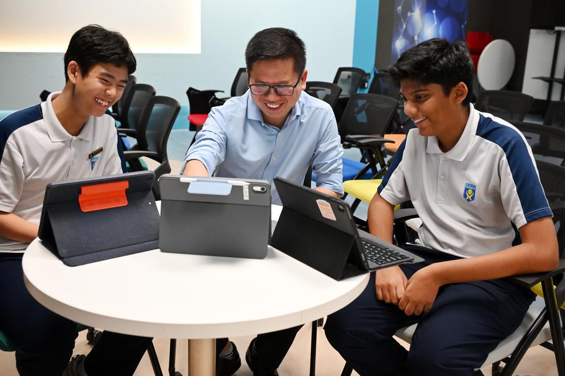 Mr Neo Guang Xian (centre) with Secondary 3 students William Teh (left) and Jain Arnav at a computing lesson at Ngee Ann Secondary School.