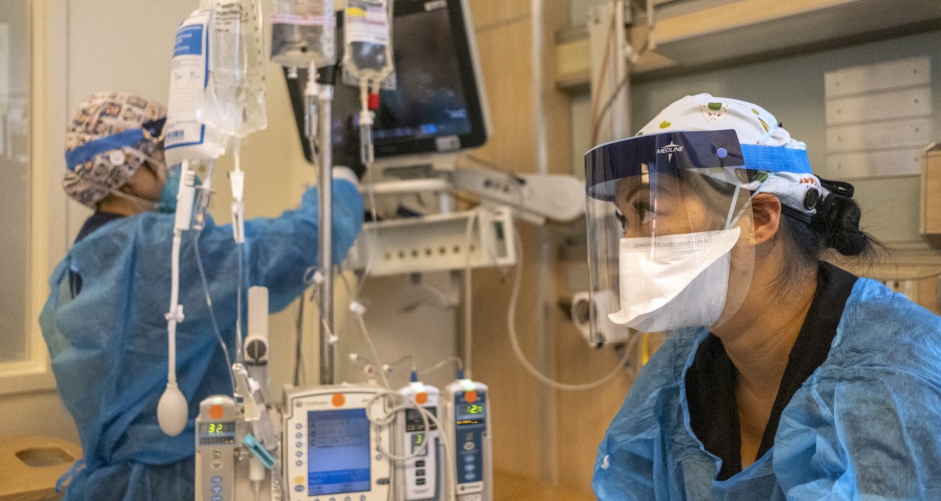 two nurses wearing protective equipment work in the ICU