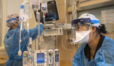 two nurses wearing protective equipment work in the ICU