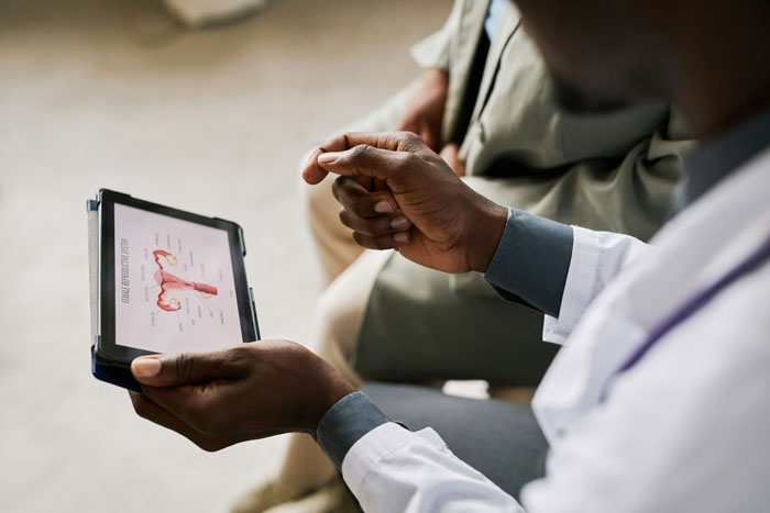 Doctor reviewing medical images on tablet, discussing rare case of hair and teeth growth inside child with patient.