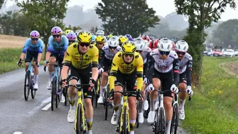 SWpix.com Dozens of cyclists race through a country road with race support cars travelling behind them. 