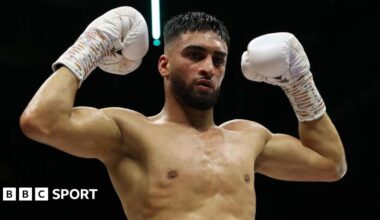 Adam Azim holds up his boxing gloves celebrating