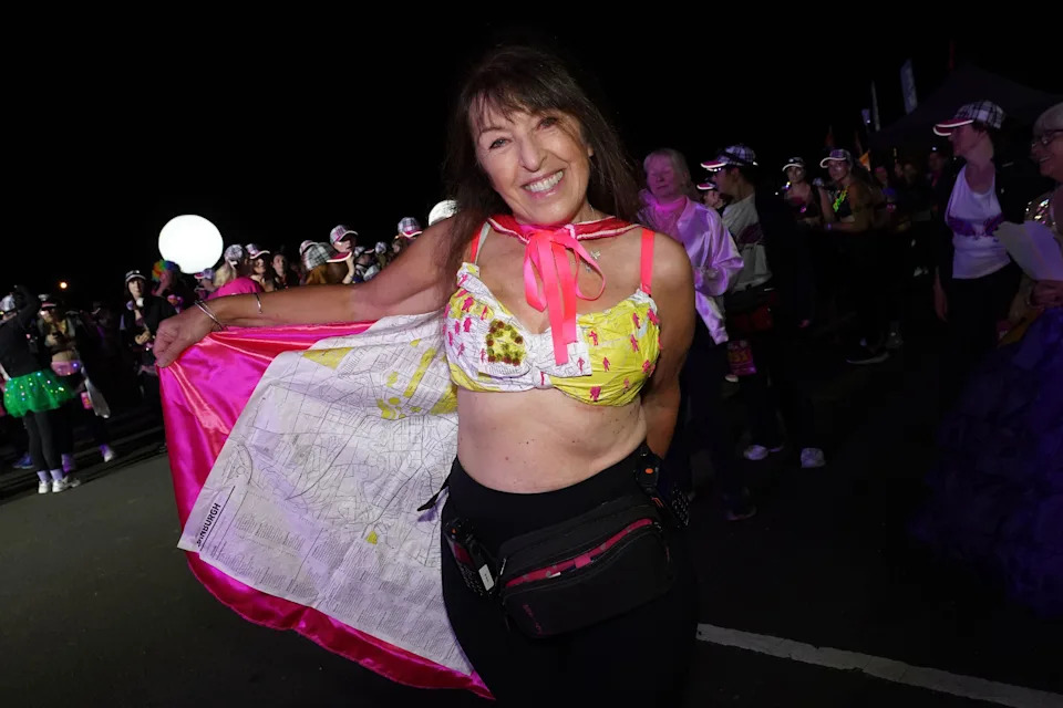 A woman with dark hair and a colourful bra smiles into the camera