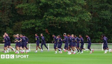 A group of players running across a football pitch during training