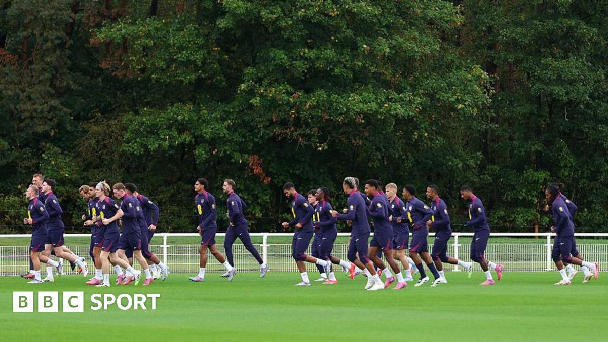 A group of players running across a football pitch during training
