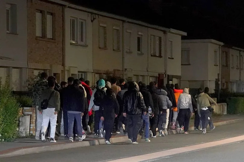 A group of people thought to be migrants walk to launch a small boat from a riverbank in Gravelines, France. Picture date: Friday September 19, 2025.