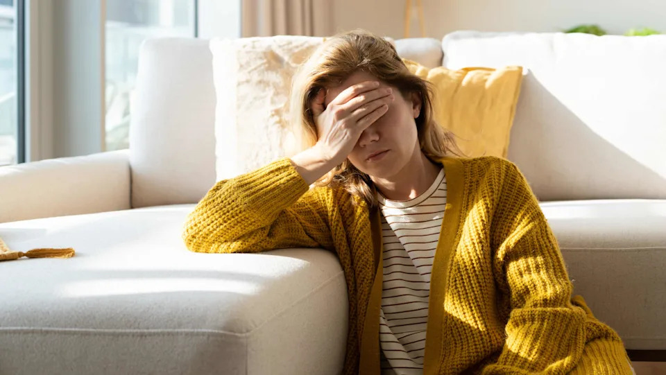 Woman suffering headache holding her head at home