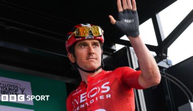 Geraint Thomas wears a red top and black shorts and he cycles past crowds of people