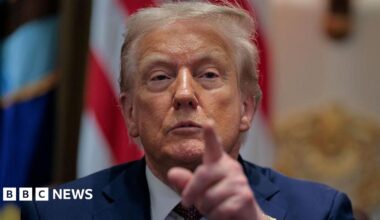 US President Donald Trump calls on a reporter during a cabinet meeting in the White House. Dressed in a navy blue blazer, he is pictured pointing towards the camera.