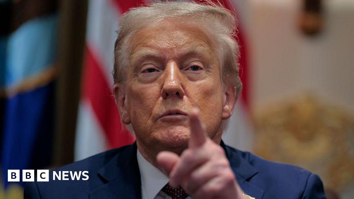 US President Donald Trump calls on a reporter during a cabinet meeting in the White House. Dressed in a navy blue blazer, he is pictured pointing towards the camera.