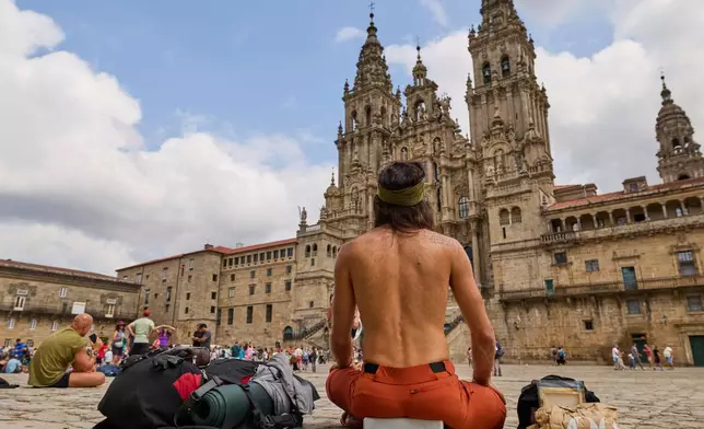 Pilgrims and tourists rest in front of the cathedral in Santiago de Compostela, northwestern Spain, Thursday, Aug. 21, 2025. (AP Photo/Lalo Villar)