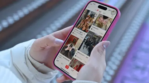 Getty Images A close-up picture of a woman holding a phone with Chinese social media app Xiaohongshu loaded on the screen