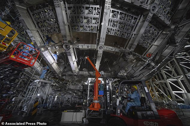 Workers labor on the underside of the cosmic detector. This futuristic underground observatory has been built with the sole purpose of detecting neutrinos – tiny cosmic particles with a mind-bogglingly small mass