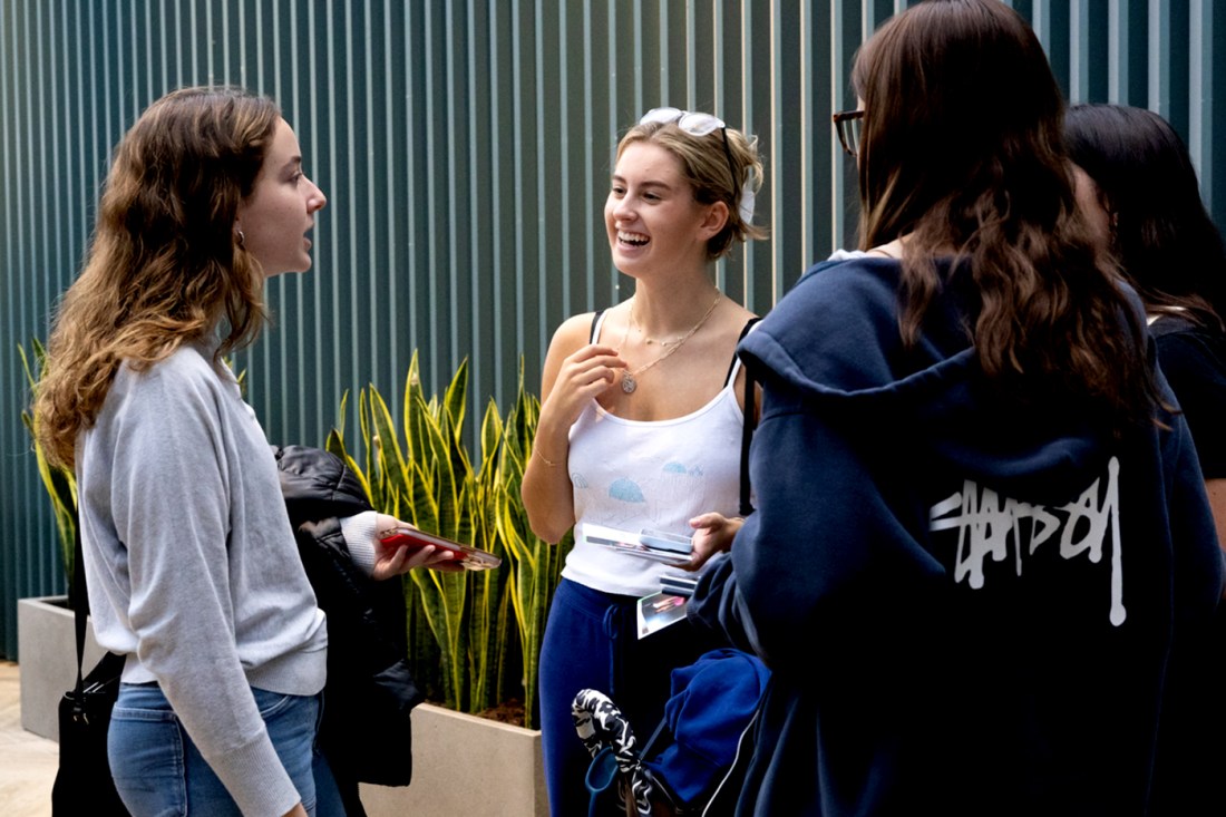 Three students having a casual conversation in a university building. 