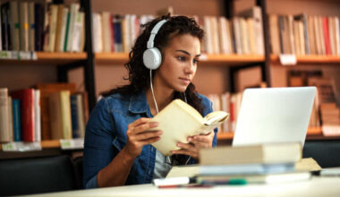 women wearing headphones and looking at computer