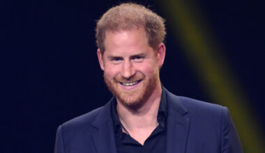 Prince Harry smiles while wearing a navy suit