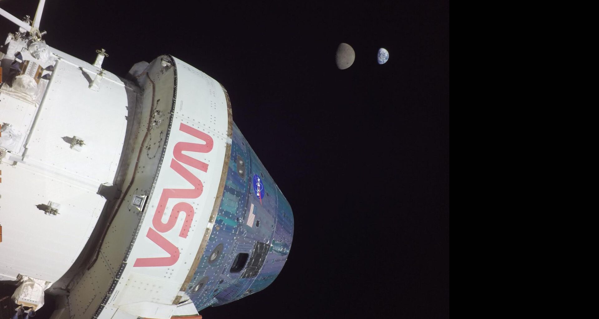 A large white space shuttle labeled in red &quot;NASA&quot; is seen in the darkness of space.