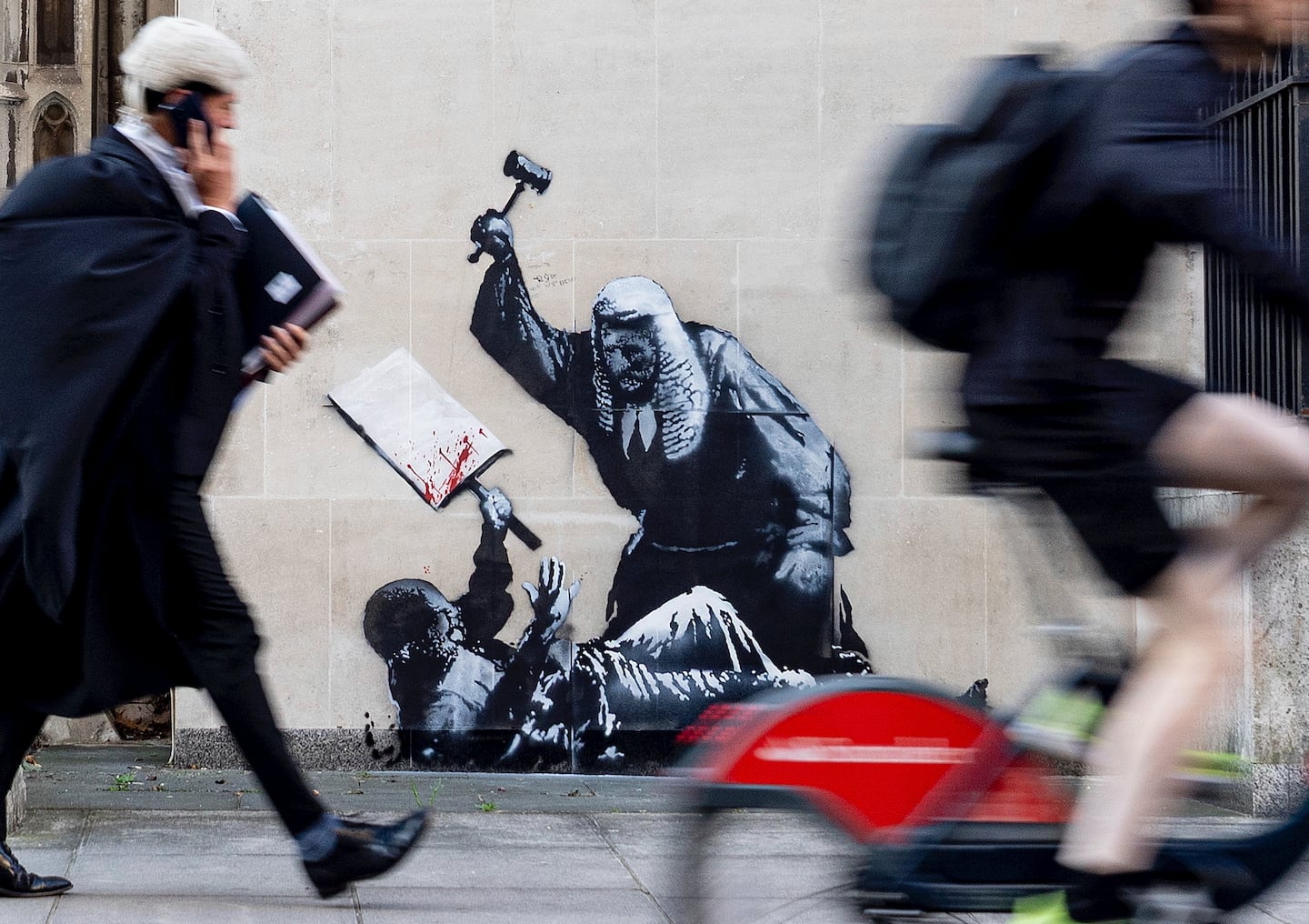 The mural depicts a protester lying on the ground holding a blood-splattered placard while a judge in a traditional wig and black gown beats him with a gavel.