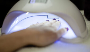 Woman Fliling Nails With UV Lamp in Background.