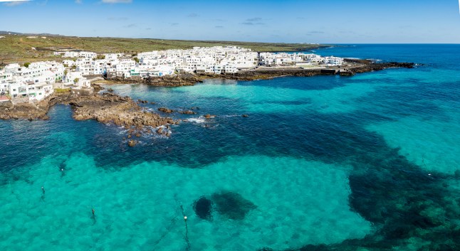 A pretty view of the white buildings and turquoise waters along the shore of Punta Mujeres, in Lanzarote, Canary Islands.