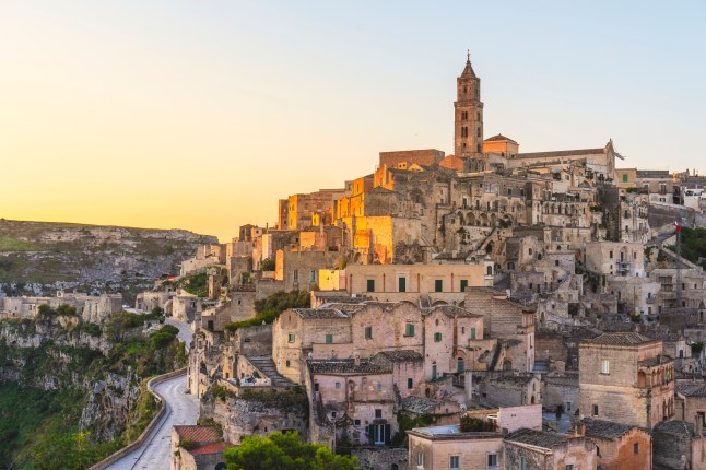 A view of the hilly Historic City of Matera and its stone buildings during sunrise.