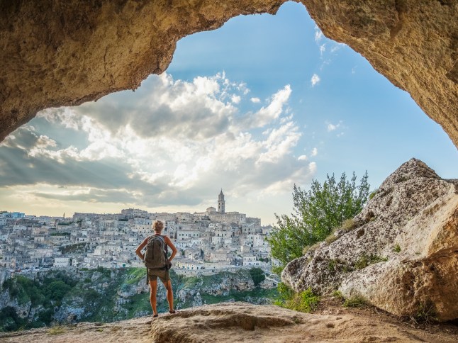 Woman hiker looking city of Matera from a cave on the hill