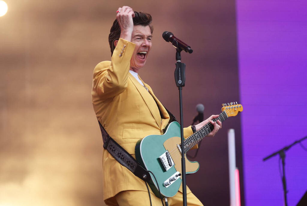 Rick Astley playing on stage at a festival