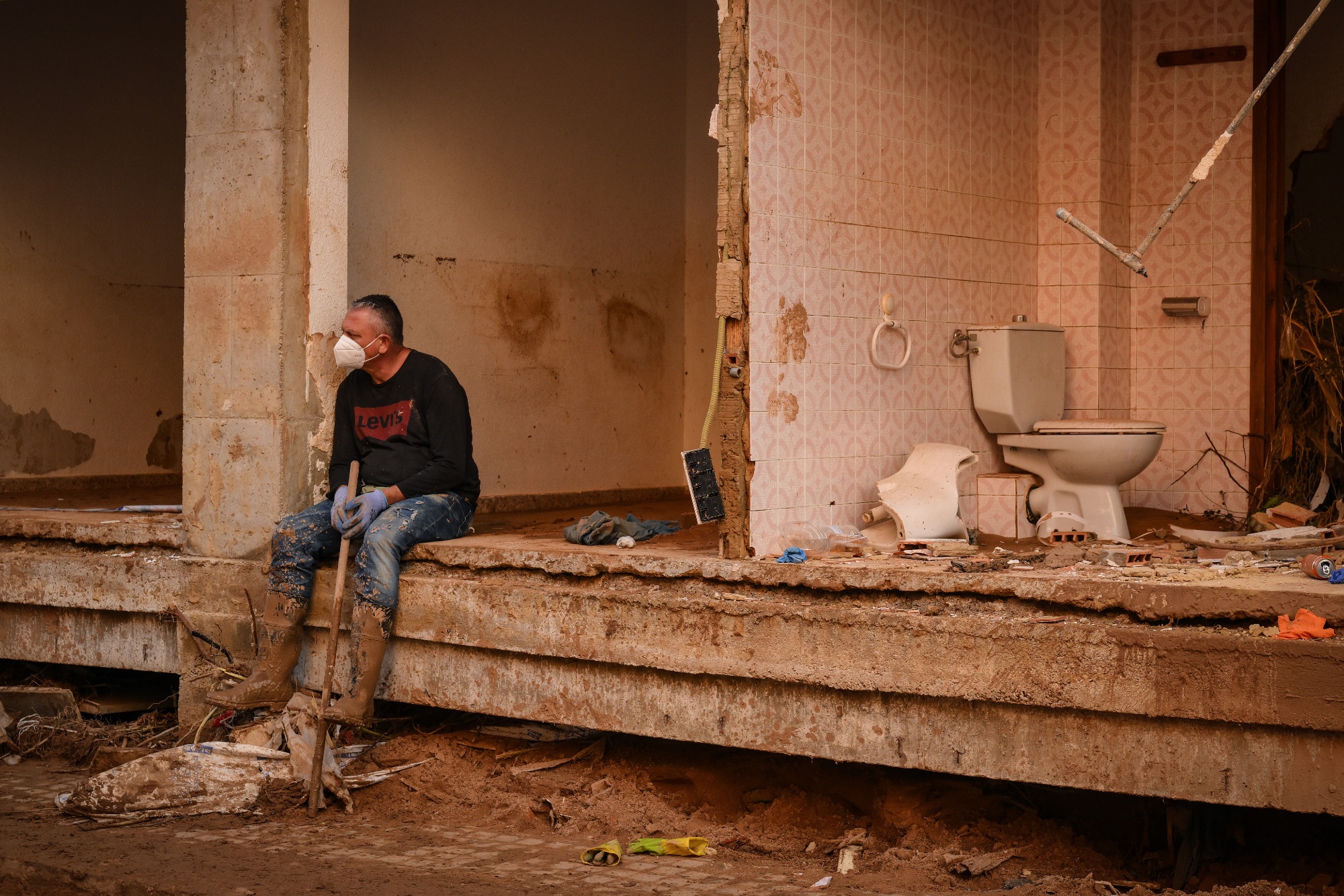 A resident sits on a wall of a collapsed house damaged by widespread flooding near Valencia, Spain in November 2024.