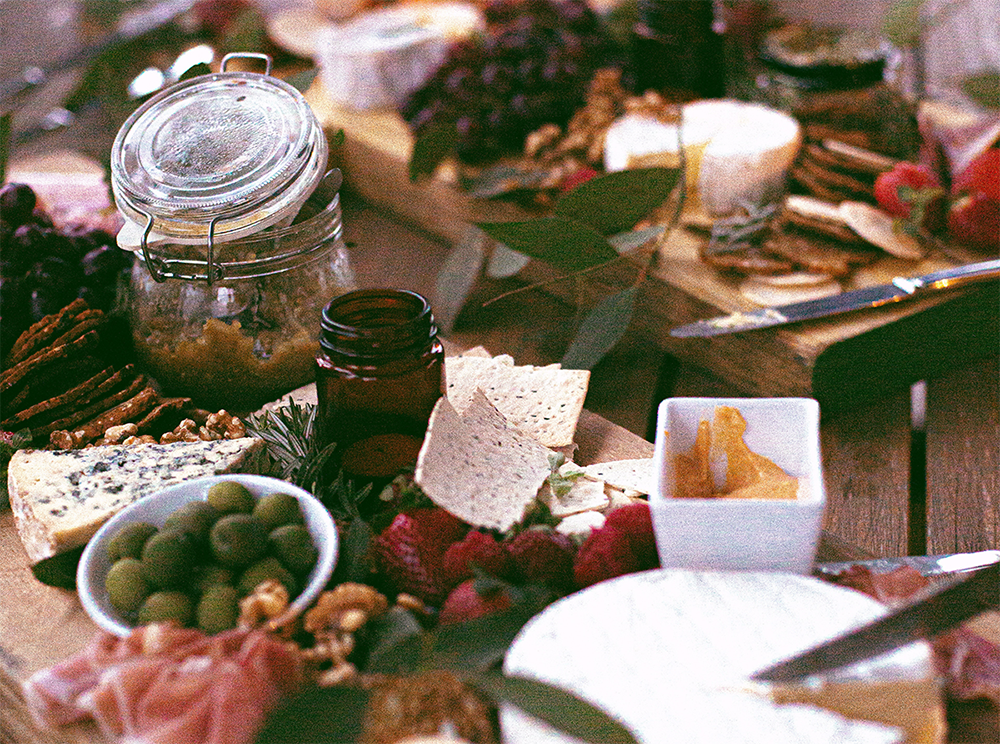 A spread of holiday dishes laid out on a table - meats, cheeses, nuts and more.