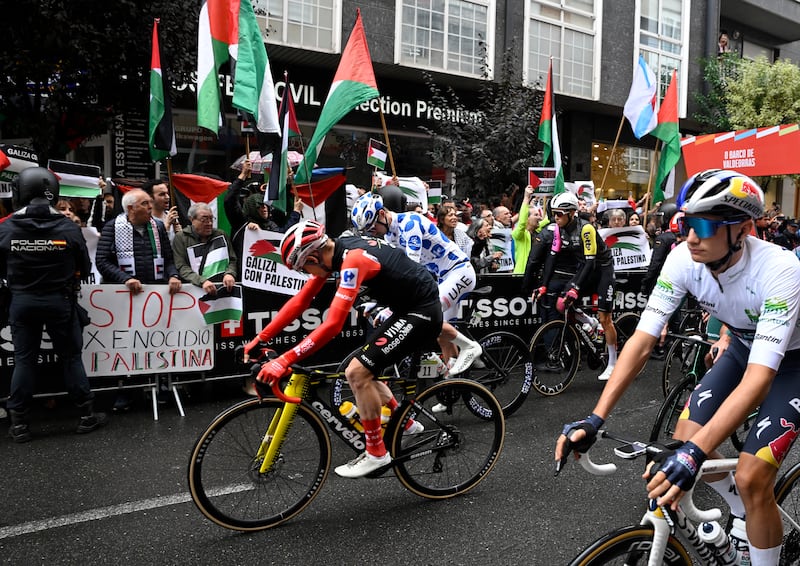 Protesters wave Palestinian flags as riders take the start of the 17th stage of the Vuelta a Espana. Photograph: Miguel Riopa/AFP via Getty Images         