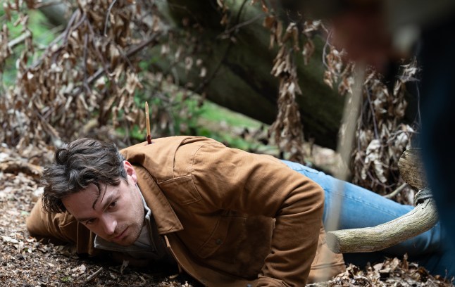 Mack tries to crawl on the woodland floor after being shot with an arrow in Emmerdale