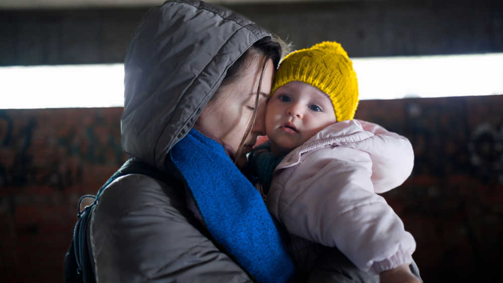 A women with her eyes closed holding a child in her arms.